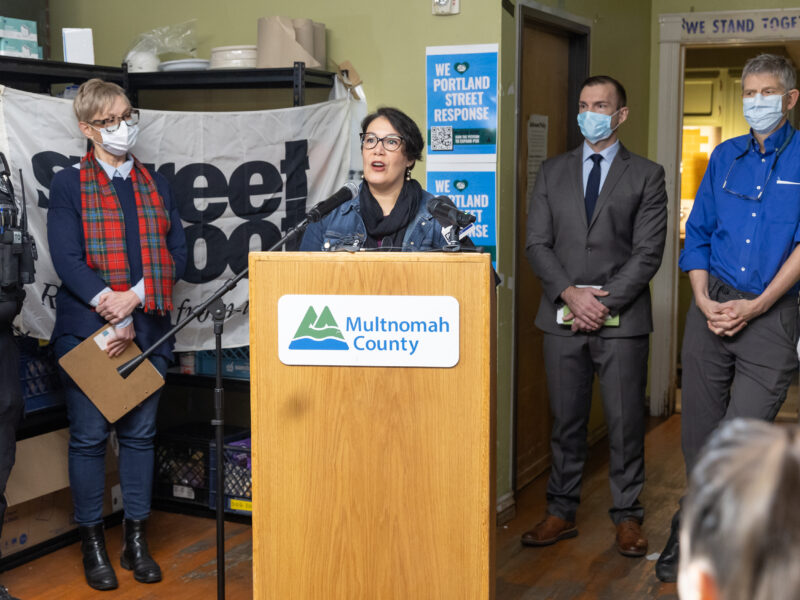 Jessica Vega Pederson stands at a dais with the Multnomah County logo
